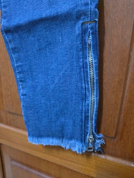 Calça jeans skinny destroyed com zíper na barra